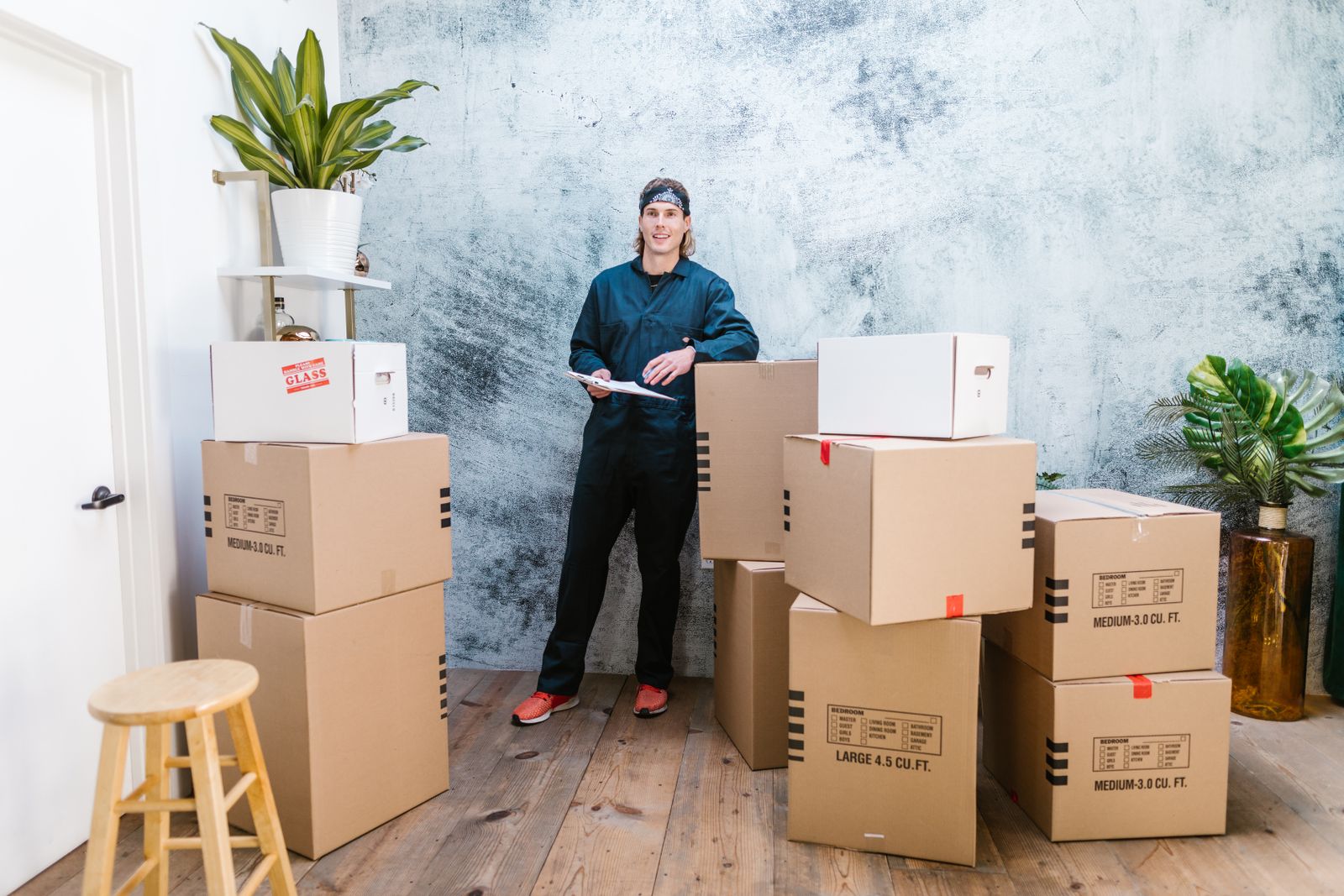 A mover checking an inventory list against packed boxes